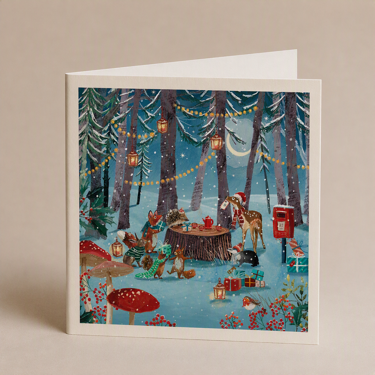 Square Christmas card featuring woodland animals having a tea party in a snowy forest with satin finish.