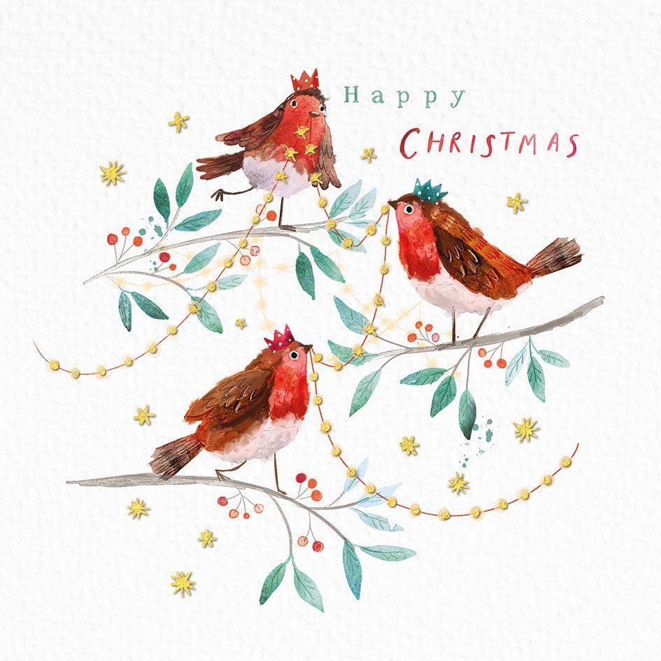 Three robins wearing festive crowns perched on snowy branches with gold foil stars and berries on a white Christmas card.