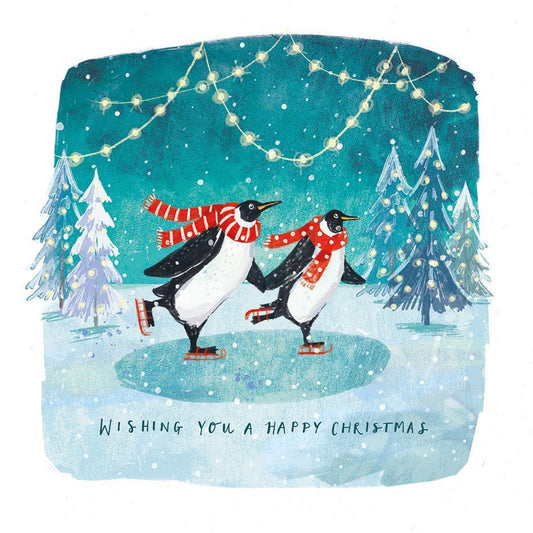 Two penguins in red scarves ice skating on a frozen pond with snowy trees and fairy lights on a square Christmas card.