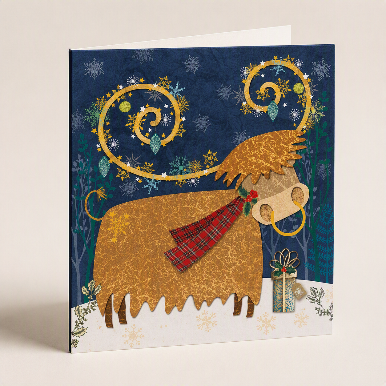 Highland cow Christmas card with a red tartan scarf, golden swirls, and a gift on a snowy blue background.